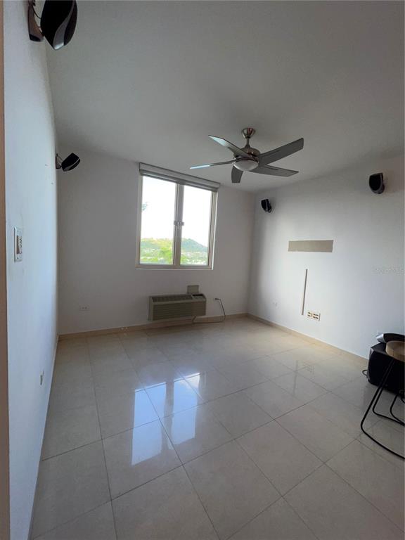 An empty room features white walls, tile flooring, a ceiling fan, and a window — 1 AVENIDA PALMA REAL UNIT 404, GUAYNABO, PR