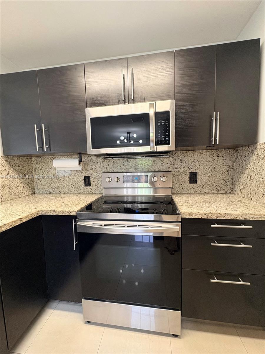A kitchen features dark wood cabinets, granite countertops, and stainless steel appliances — 1116 N 61st Ave # 1, Hollywood FL 33024, HOLLYWOOD, FL