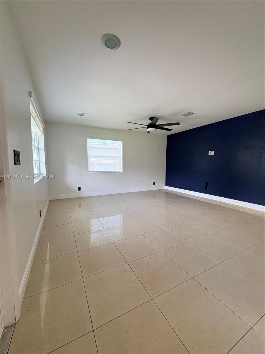 An empty room features light-colored tile flooring, white walls, and a dark blue accent wall — 1116 N 61st Ave # 1, Hollywood FL 33024, HOLLYWOOD, FL