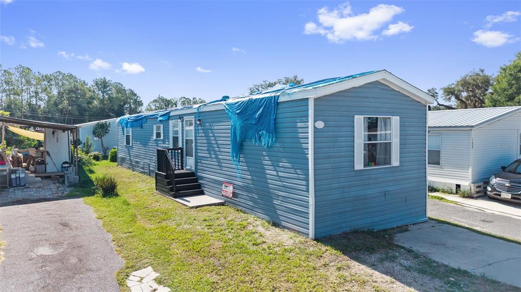 A blue mobile home with a blue tarp on its roof sits on a lot — 11535 LEANNE LANE UNIT 160, TAMPA, FL