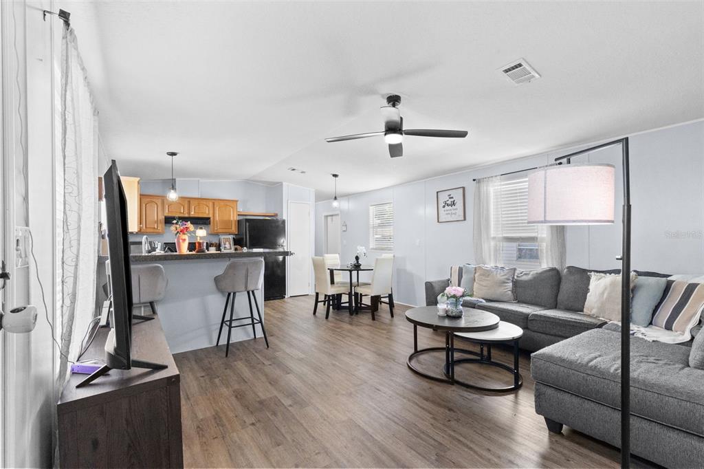An open-concept living room and kitchen featuring wood-look flooring, a gray sectional, and bar seating — 11535 LEANNE LANE UNIT 160, TAMPA, FL