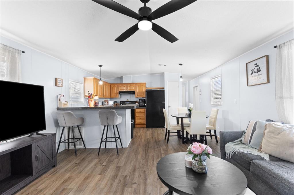 A living room and kitchen area with wood-look flooring, a ceiling fan, and bar seating — 11535 LEANNE LANE UNIT 160, TAMPA, FL