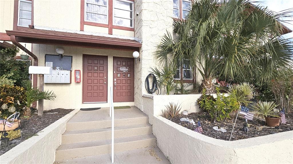 The exterior of a multi-unit building features two brown doors, concrete steps, and landscaping — 93 BOUNDARY BOULEVARD UNIT 303, ROTONDA WEST, FL