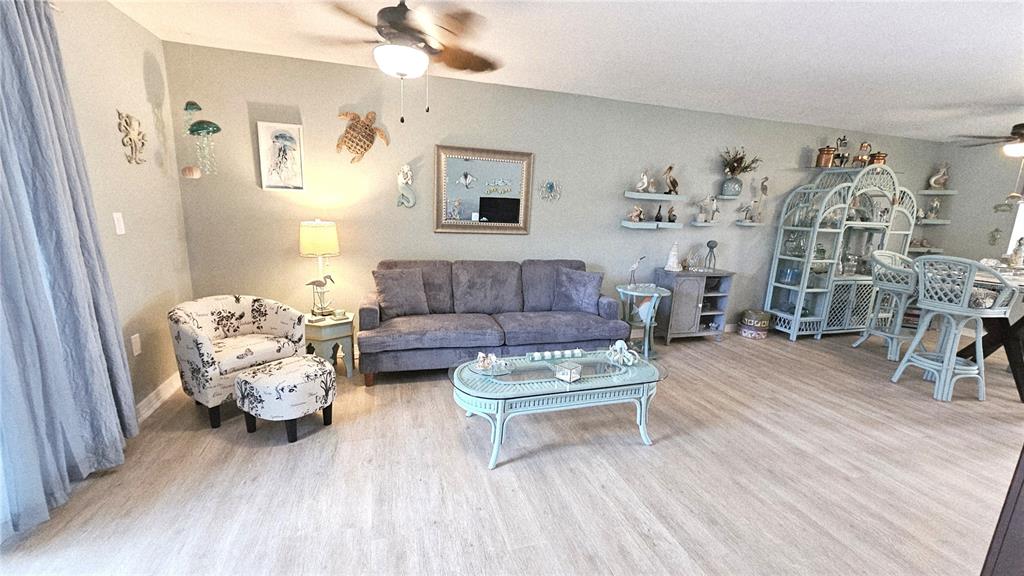 A living room features a gray sofa, patterned armchair, wicker coffee table, and coastal decor — 93 BOUNDARY BOULEVARD UNIT 303, ROTONDA WEST, FL