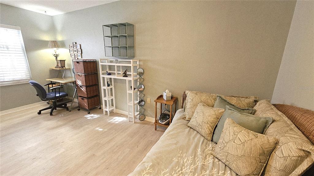 A room with light wood flooring, a desk, a daybed, and various storage shelving units — 93 BOUNDARY BOULEVARD UNIT 303, ROTONDA WEST, FL