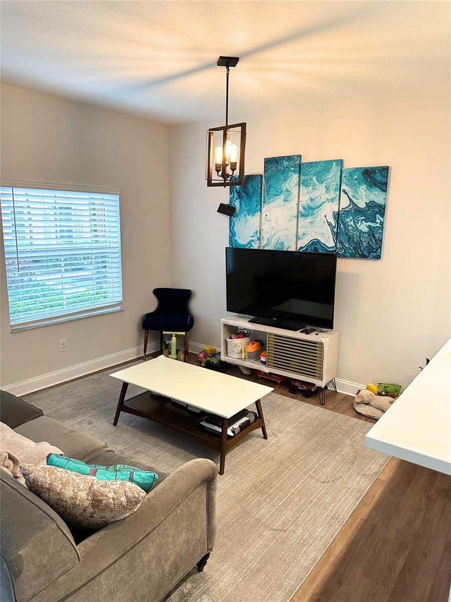 A living room features a grey sofa, a coffee table, a television, and blue wall art — 2319 Clipper Place # 4510, Dania Beach FL 33312, DANIA BEACH, FL