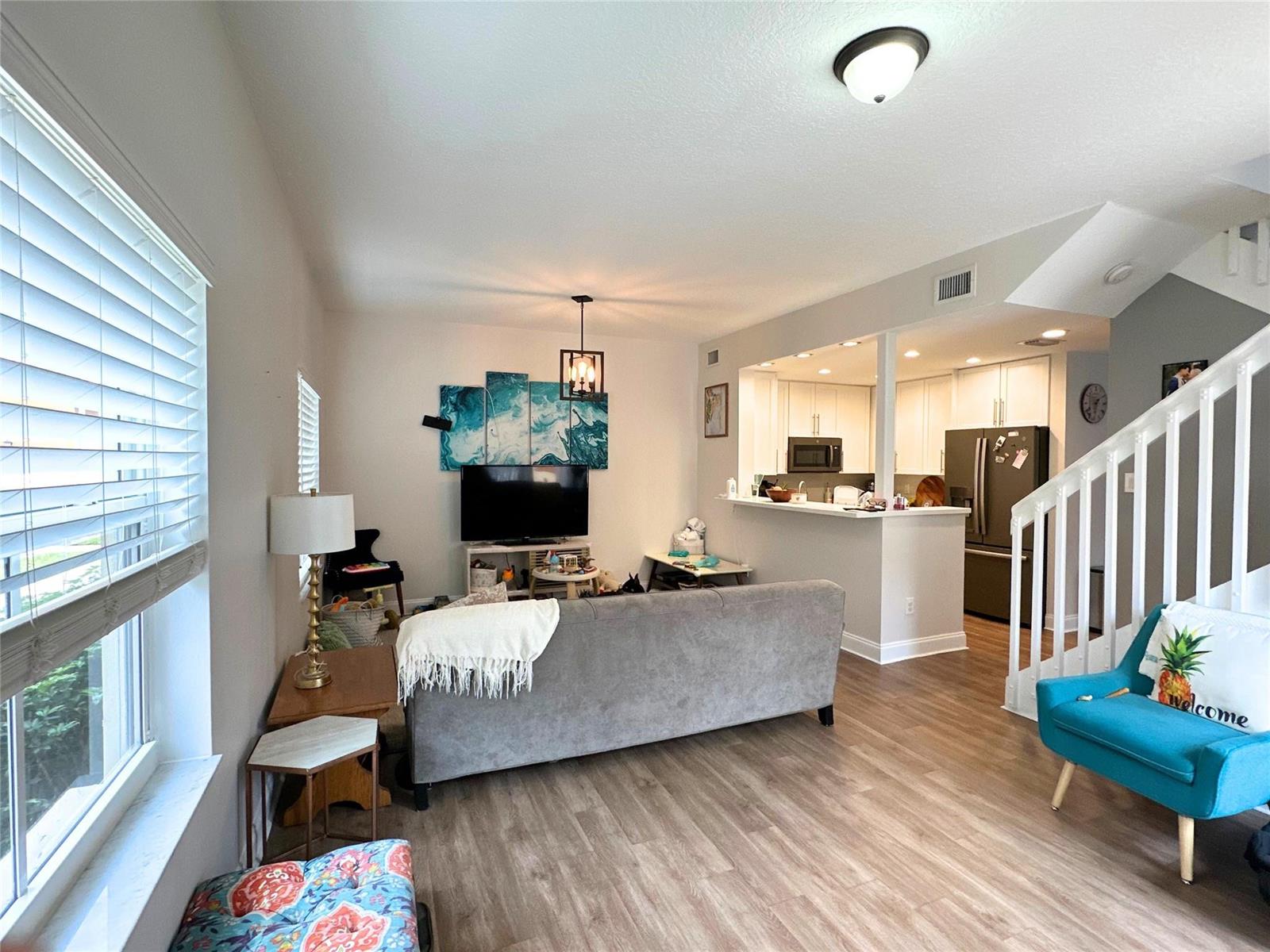 A living room with wood-look flooring, a gray sofa, and an open kitchen area — 2319 Clipper Place # 4510, Dania Beach FL 33312, DANIA BEACH, FL