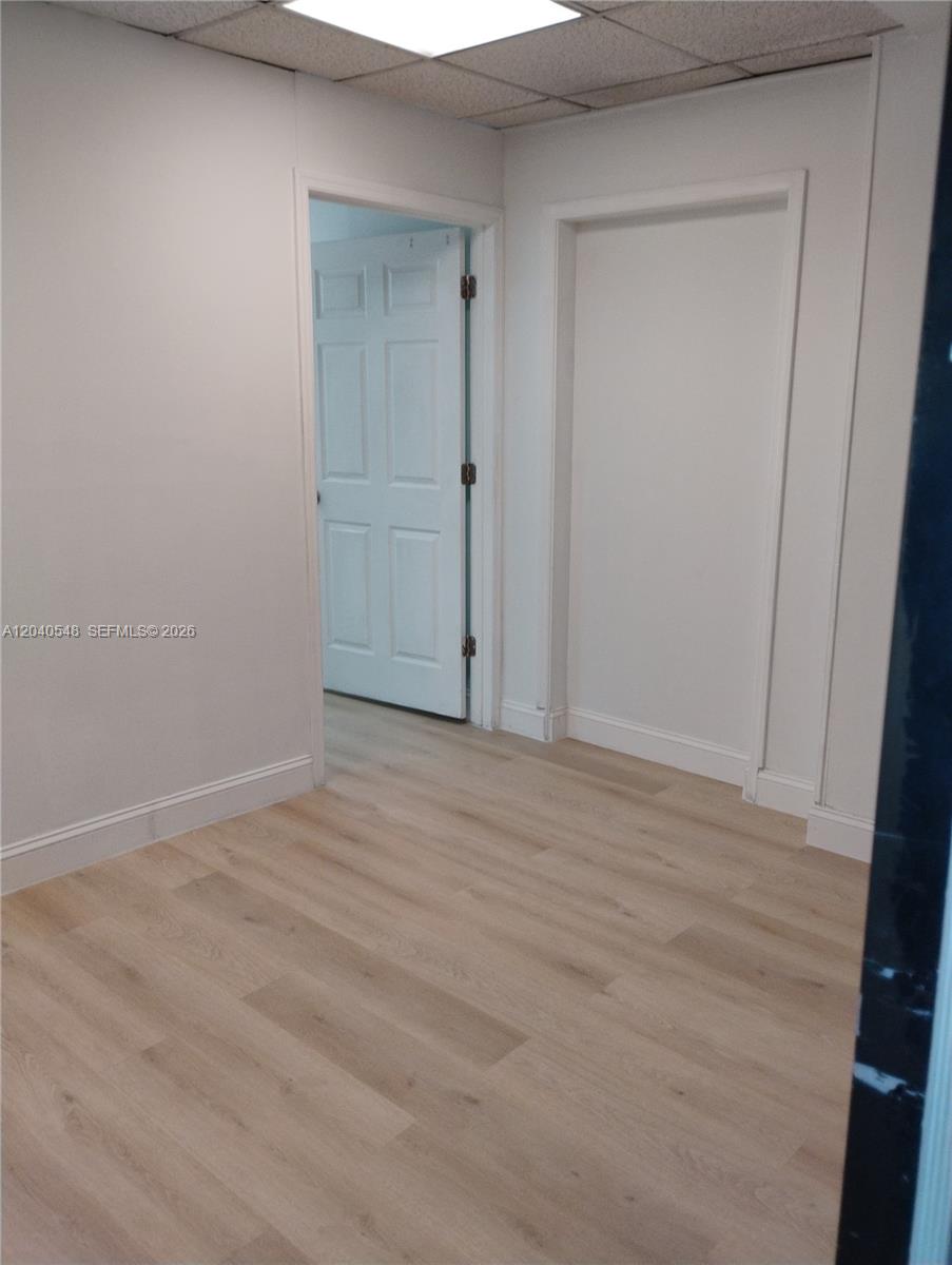An interior room features light wood-look flooring, white walls, and a single open doorway — 285 NW 27th Ave, Miami FL 33125, MIAMI, FL