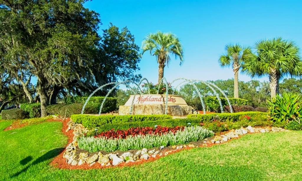 A stone monument sign for Highland Lakes sits in a landscaped garden with a fountain — 26912 BECKER COURT, LEESBURG, FL