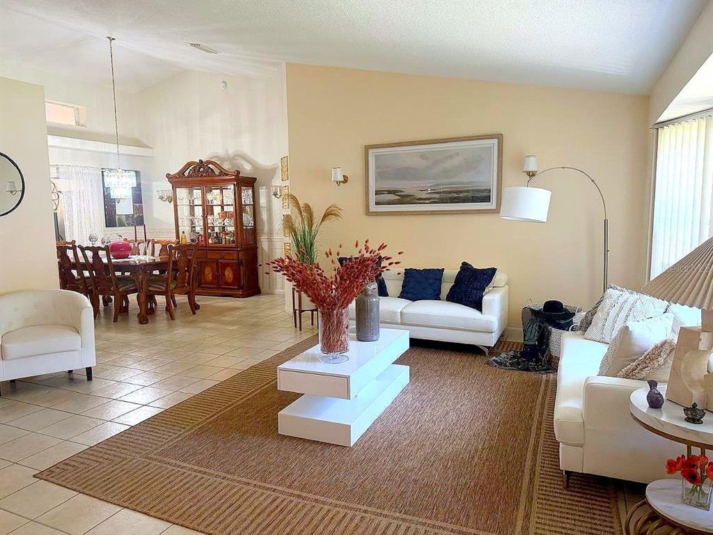 A living room with white sofas, a tiered coffee table, and an adjacent dining area — 26912 BECKER COURT, LEESBURG, FL