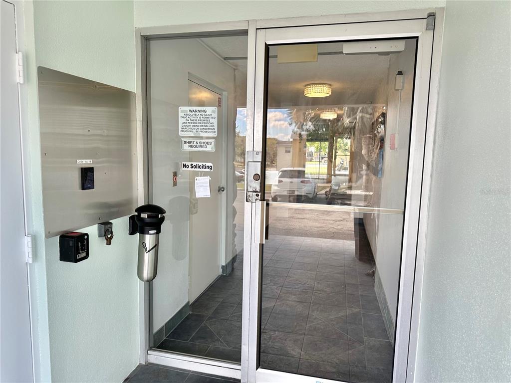 A glass-paneled entrance door with signage leads into a tiled lobby area — 100 WAVERLY WAY UNIT 302, CLEARWATER, FL