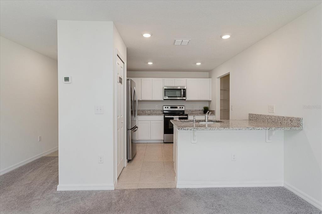 A kitchen with white cabinets, granite countertops, stainless steel appliances, and a breakfast bar — 352 TOWNS CIRCLE, HAINES CITY, FL