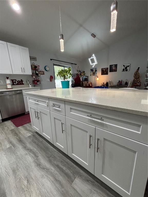 A kitchen island with white cabinets and a light-colored countertop sits on wood-look flooring — 13849 SW 105TH PLACE, DUNNELLON, FL