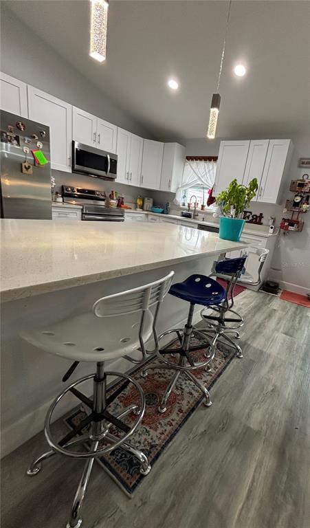 A kitchen features white cabinets, a quartz island, and three metal bar stools — 13849 SW 105TH PLACE, DUNNELLON, FL