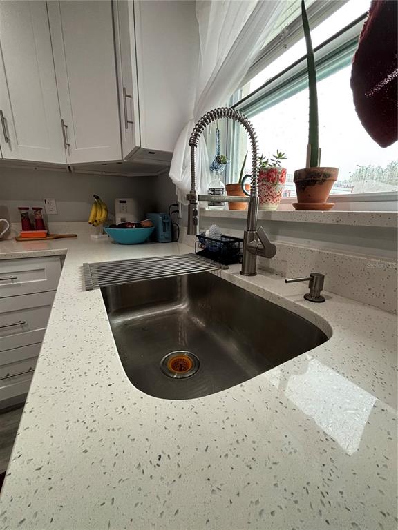 A kitchen sink with a high-arc faucet and speckled white countertops sits before a window — 13849 SW 105TH PLACE, DUNNELLON, FL