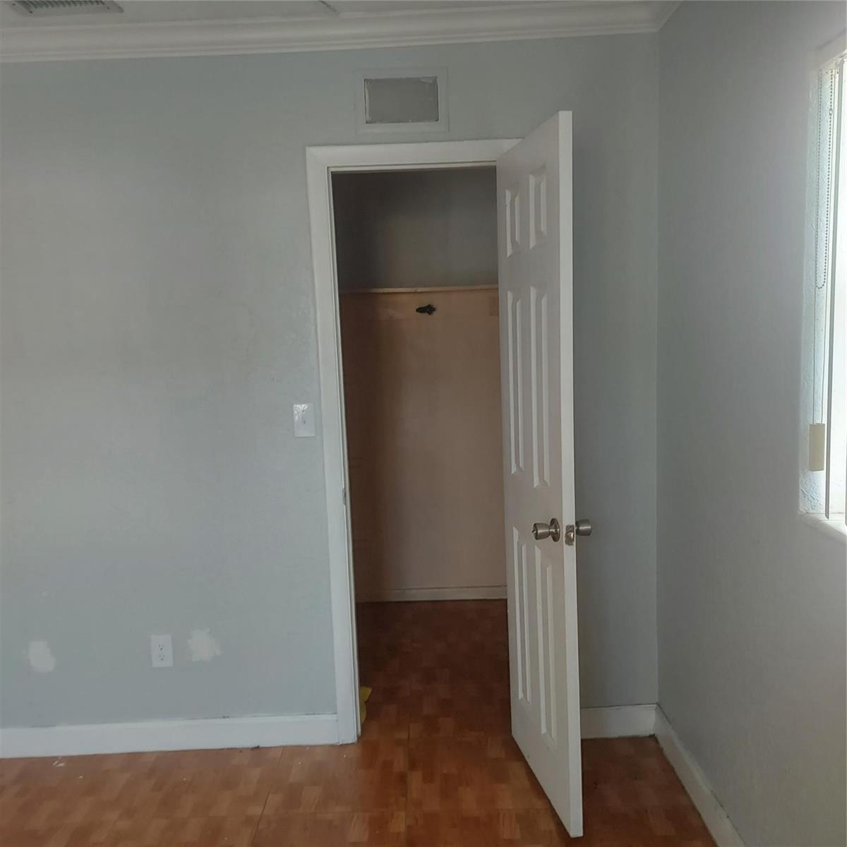 A room with light gray walls, wood-look flooring, and an open closet door — LAUDERDALE LAKES, FL