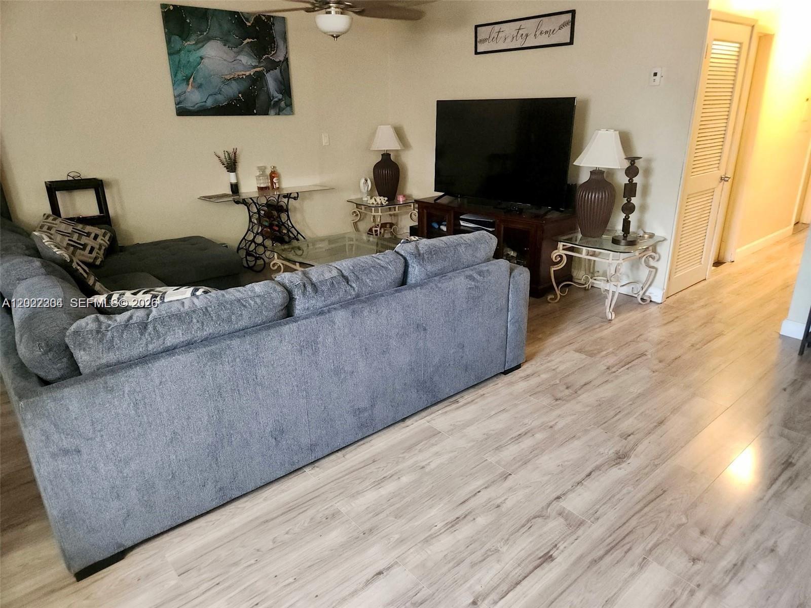 A living room features a grey sectional sofa, a television on a stand, and wood-look flooring — 4851 NW 11th Ct, Lauderhill FL 33313, LAUDERHILL, FL