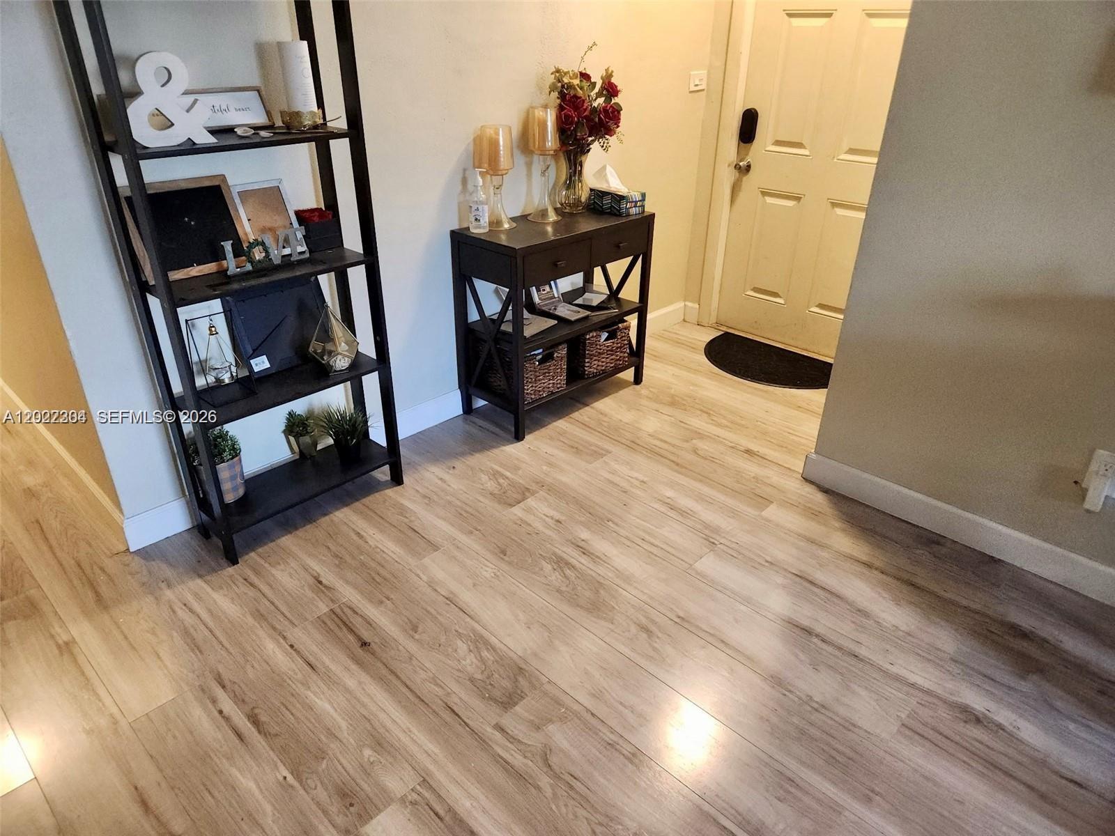 An entryway features light wood-look flooring, a tall black shelving unit, and a console table — 4851 NW 11th Ct, Lauderhill FL 33313, LAUDERHILL, FL