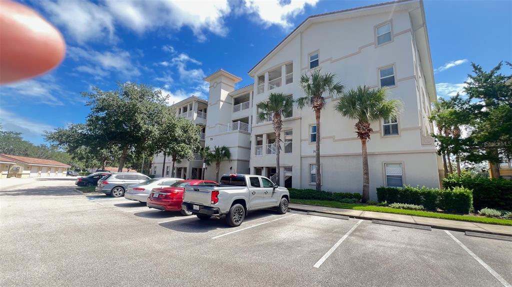 A multi-story apartment building with a parking lot and several parked cars in front — 75 RIVERVIEW BEND S UNIT 1642, PALM COAST, FL