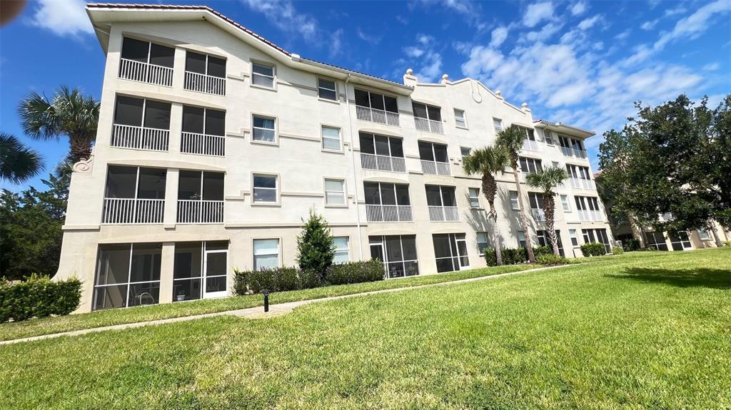 A multi-story apartment building with screened balconies and a lawn in the foreground — 75 RIVERVIEW BEND S UNIT 1642, PALM COAST, FL