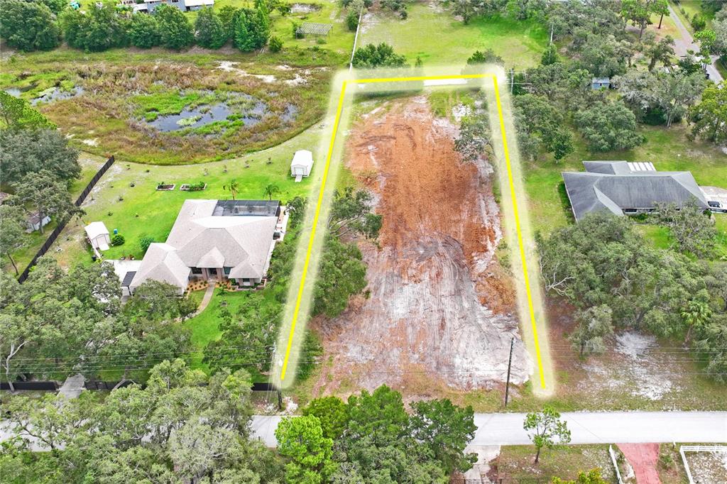 An aerial view shows a cleared, rectangular vacant lot outlined in yellow between two houses — 0 LANSFORD DRIVE, HUDSON, FL