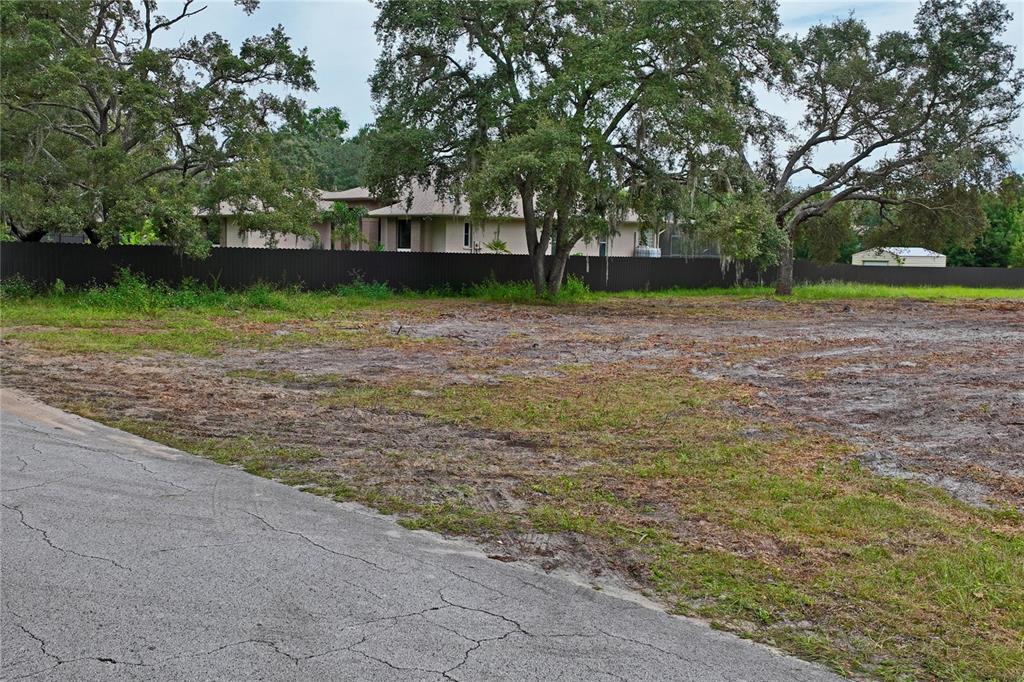 A vacant, cleared lot sits adjacent to an asphalt road with trees and a fence behind — 0 LANSFORD DRIVE, HUDSON, FL