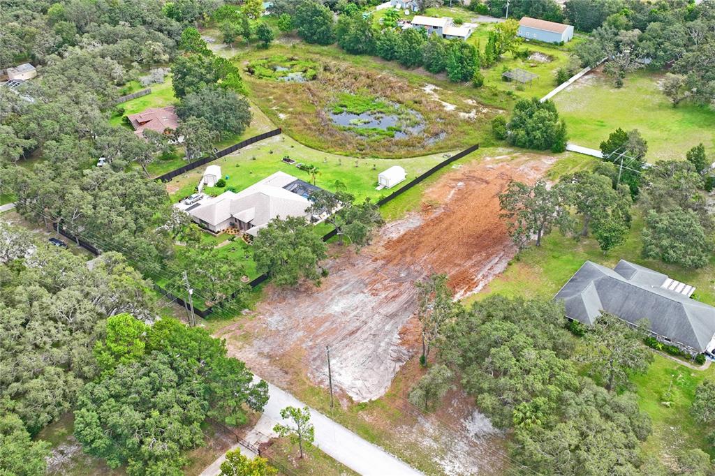 An aerial view shows a cleared residential lot adjacent to a house and a pond — 0 LANSFORD DRIVE, HUDSON, FL