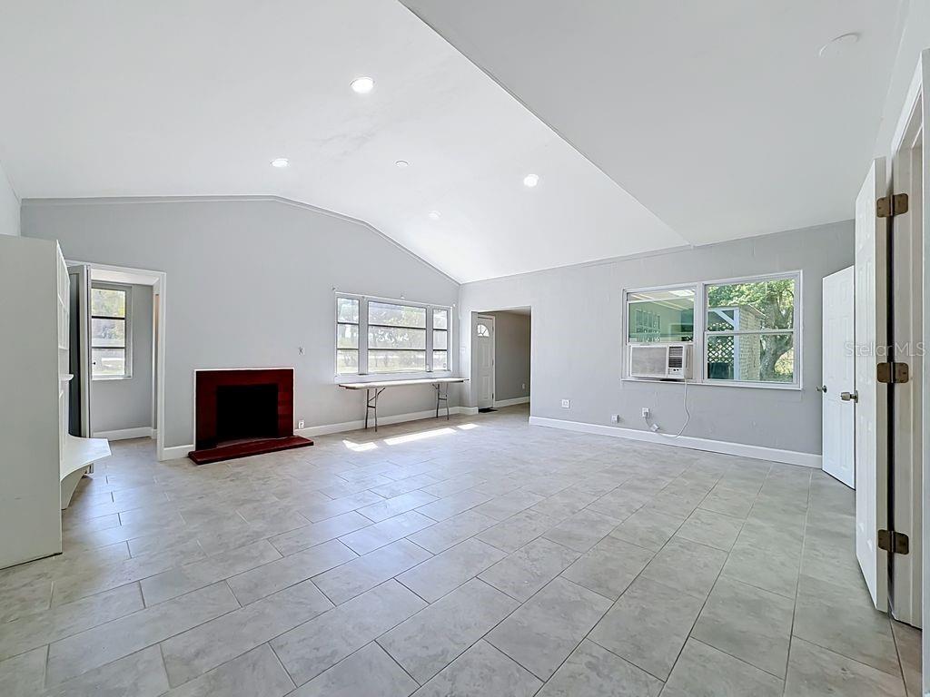 A spacious living room features light gray walls, tile flooring, a fireplace, and vaulted ceilings — 3508 ROUSE ROAD, ORLANDO, FL