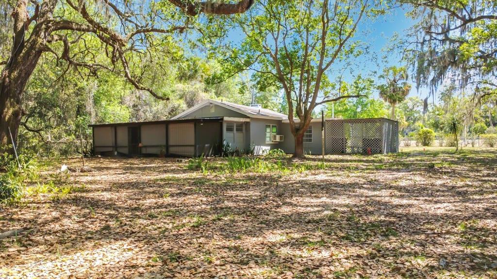 The exterior of a single-story house with a screened porch sits on a wooded lot — 3508 ROUSE ROAD, ORLANDO, FL