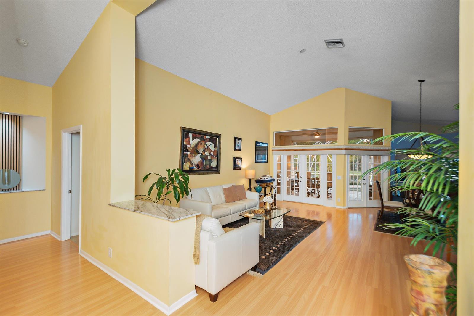 A living room features light yellow walls, vaulted ceilings, hardwood floors, and a white sofa — 412 Cameron Drive, Weston FL 33326, WESTON, FL