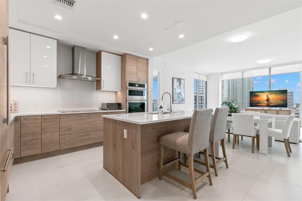 A modern kitchen with wood-tone cabinetry, white countertops, and an island with bar seating — 301 1ST STREET S UNIT 1204, ST PETERSBURG, FL