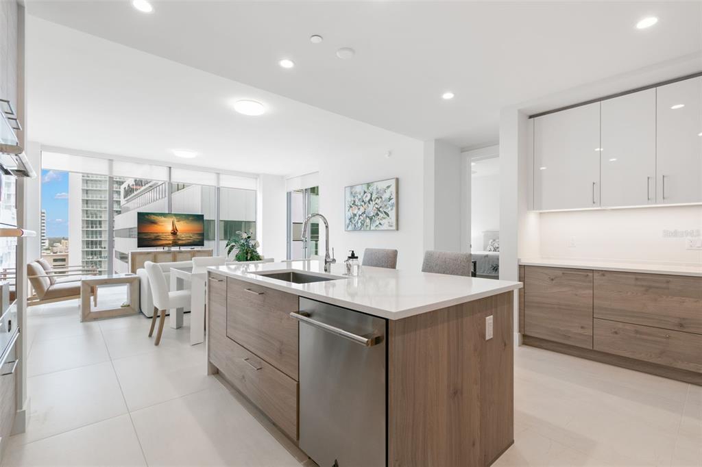A modern kitchen with a wood-toned island and white upper cabinets overlooks a living area — 301 1ST STREET S UNIT 1204, ST PETERSBURG, FL