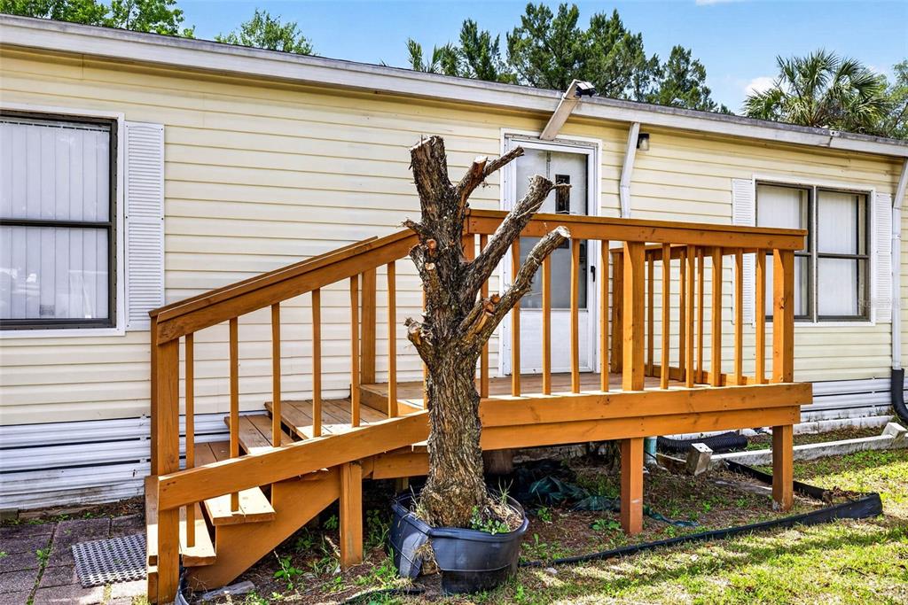 A wooden deck with stairs leads to the front door of a light-colored mobile home — 8552 W PEACOCK COURT, HOMOSASSA, FL