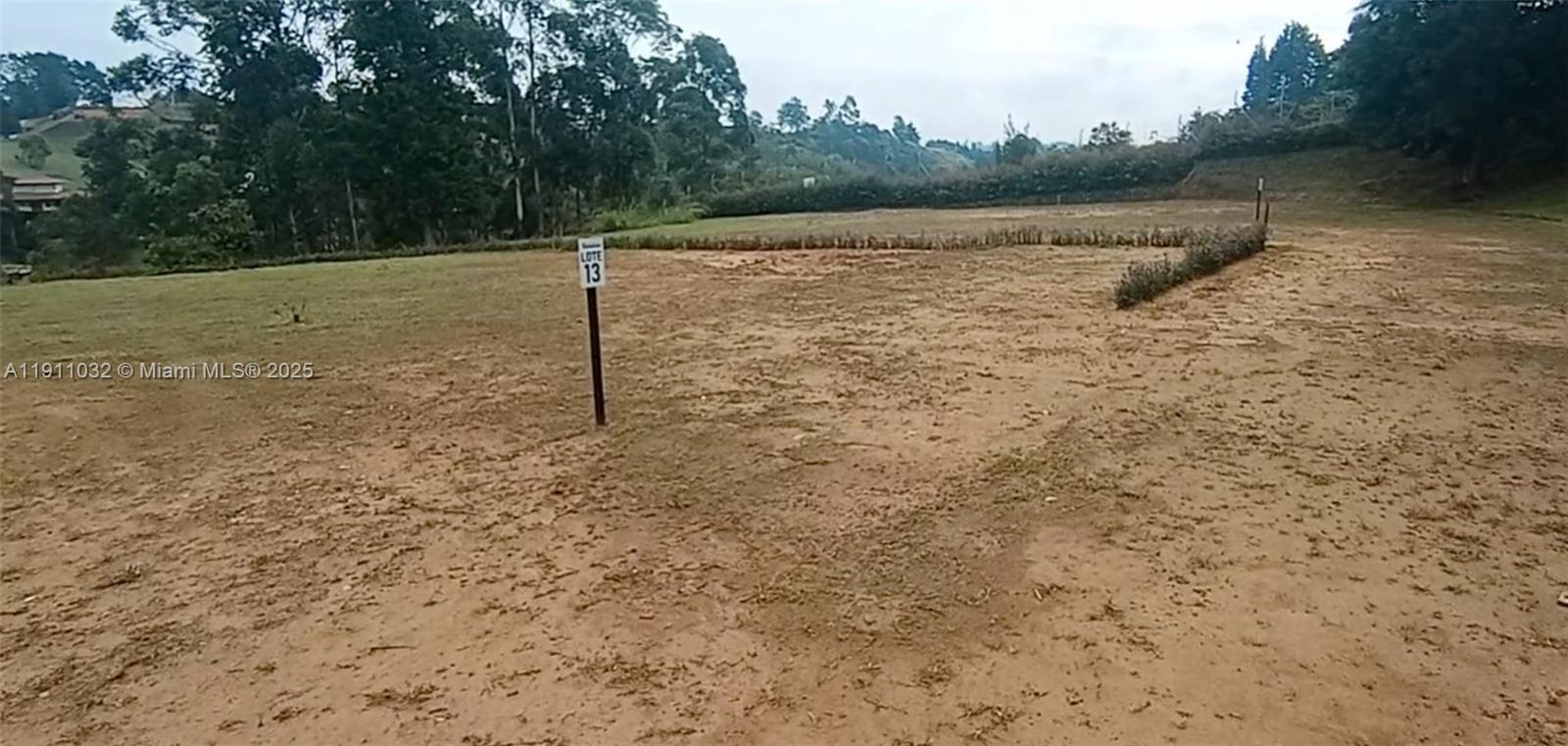 A vacant, dirt-covered lot marked with a sign labeled Lote 13 — Vereda Mampuesto Sector Garrido #13, C Colombia, C