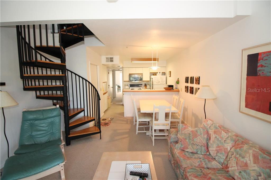 A living room with a spiral staircase, dining area, and kitchen in an open floor plan — 9400 LITTLE GASPARILLA ISLAND UNIT F9, PLACIDA, FL