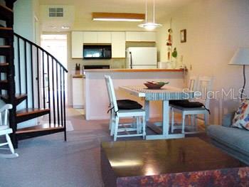 A dining area with a spiral staircase, white kitchen cabinets, and a rectangular wooden table — 9400 LITTLE GASPARILLA ISLAND UNIT F9, PLACIDA, FL