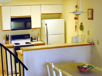 A kitchen features white cabinets, a black microwave, a white stove, and a white refrigerator — 9400 LITTLE GASPARILLA ISLAND UNIT F9, PLACIDA, FL