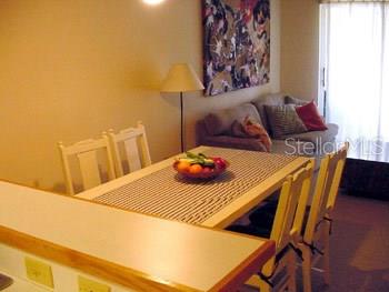 A dining area with a wooden table, four chairs, and a sofa in the background — 9400 LITTLE GASPARILLA ISLAND UNIT F9, PLACIDA, FL