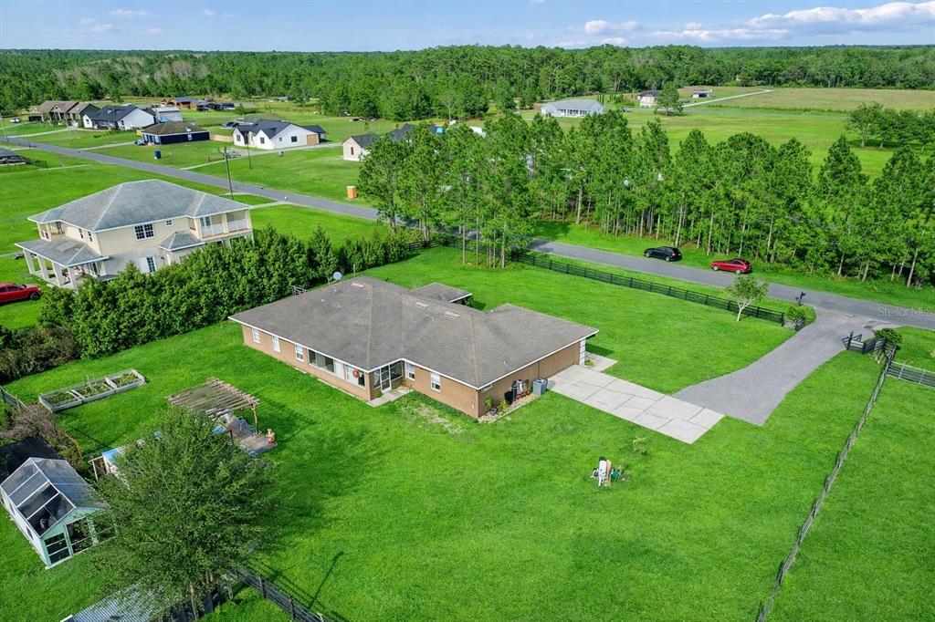 An aerial view shows a single-story house with a large yard, driveway, and surrounding landscape — 18030 BAYAMON AVENUE, POLK CITY, FL