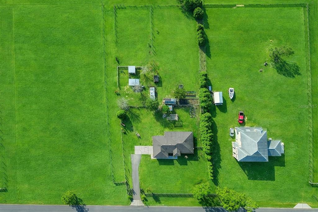An aerial view shows a house and outbuildings on a large, fenced grassy lot — 18030 BAYAMON AVENUE, POLK CITY, FL