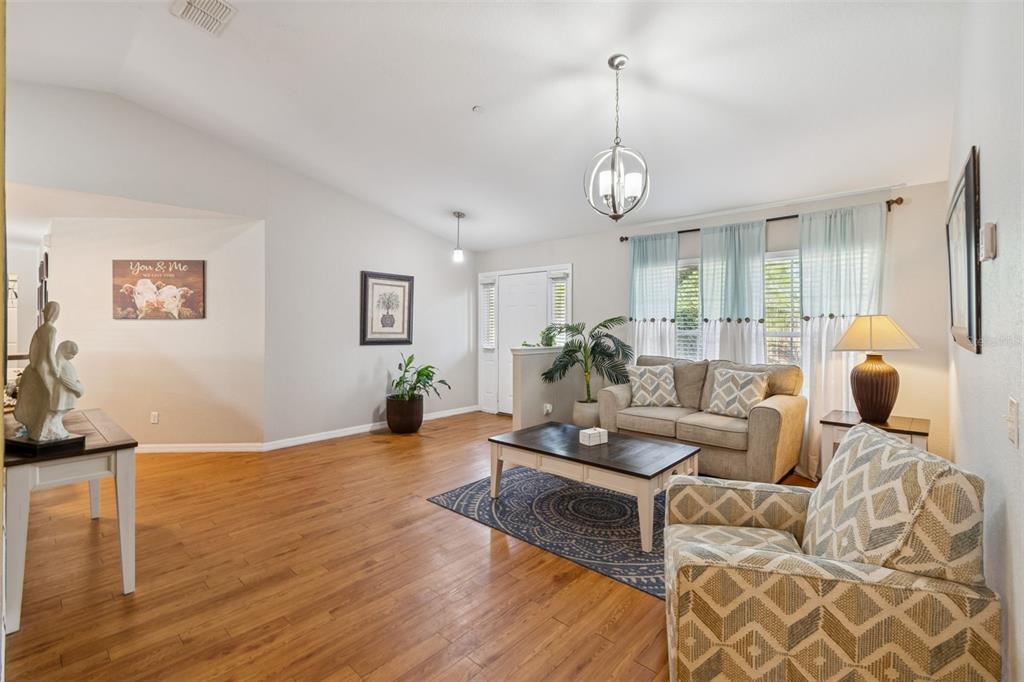 A living room features hardwood floors, a beige sofa, patterned armchair, and a coffee table — 18030 BAYAMON AVENUE, POLK CITY, FL