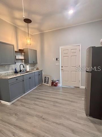 A kitchen features gray cabinets, granite countertops, a stainless steel refrigerator, and light wood flooring — 517 JERSEY AVENUE, ST CLOUD, FL