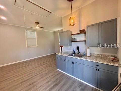A kitchen with gray cabinets and granite countertops opens into a living area with wood flooring — 517 JERSEY AVENUE, ST CLOUD, FL