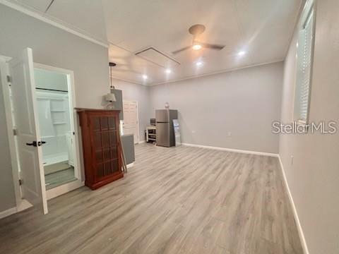 An open-concept room features light wood-look flooring, a ceiling fan, and an attached bathroom — 517 JERSEY AVENUE, ST CLOUD, FL