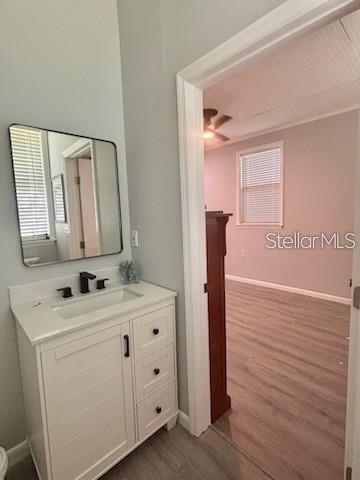 A bathroom vanity with a mirror and sink sits beside a doorway leading to a bedroom — 517 JERSEY AVENUE, ST CLOUD, FL