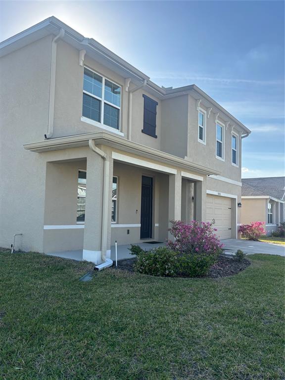 A two-story beige stucco house features a covered front porch and an attached garage — 32762 PEZ LANDING LANE, WESLEY CHAPEL, FL