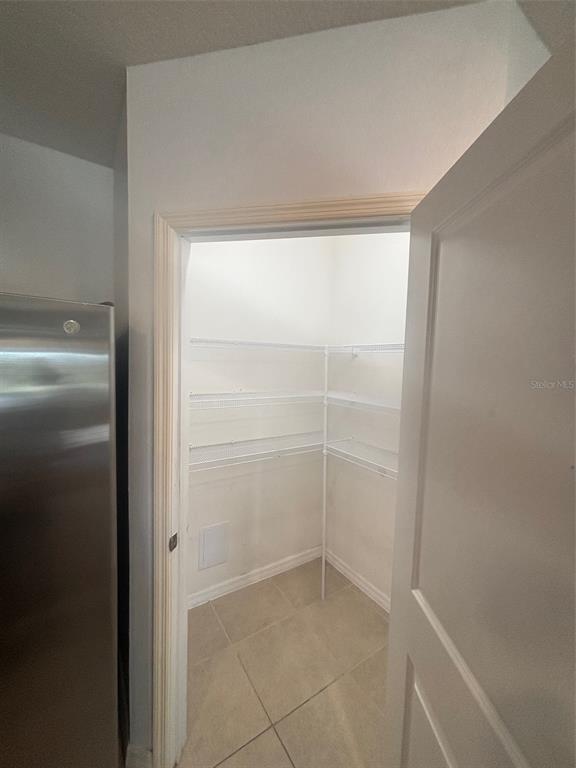 A pantry with white wire shelving and tile flooring is visible through an open door — 32762 PEZ LANDING LANE, WESLEY CHAPEL, FL