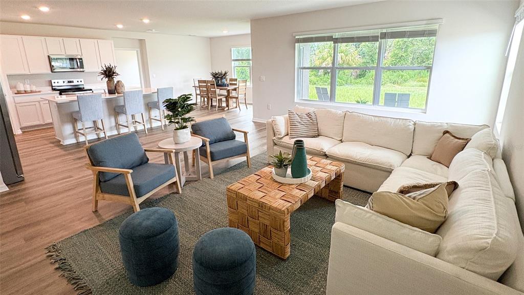 This open-concept living room features a sectional sofa, two armchairs, and a kitchen island — 17506 WHISKEY CREEK TRAIL, PARRISH, FL