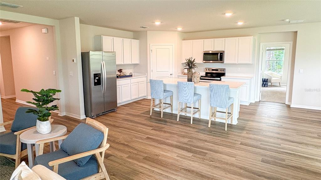 A modern kitchen features white cabinetry, stainless steel appliances, and a central island with seating — 17506 WHISKEY CREEK TRAIL, PARRISH, FL