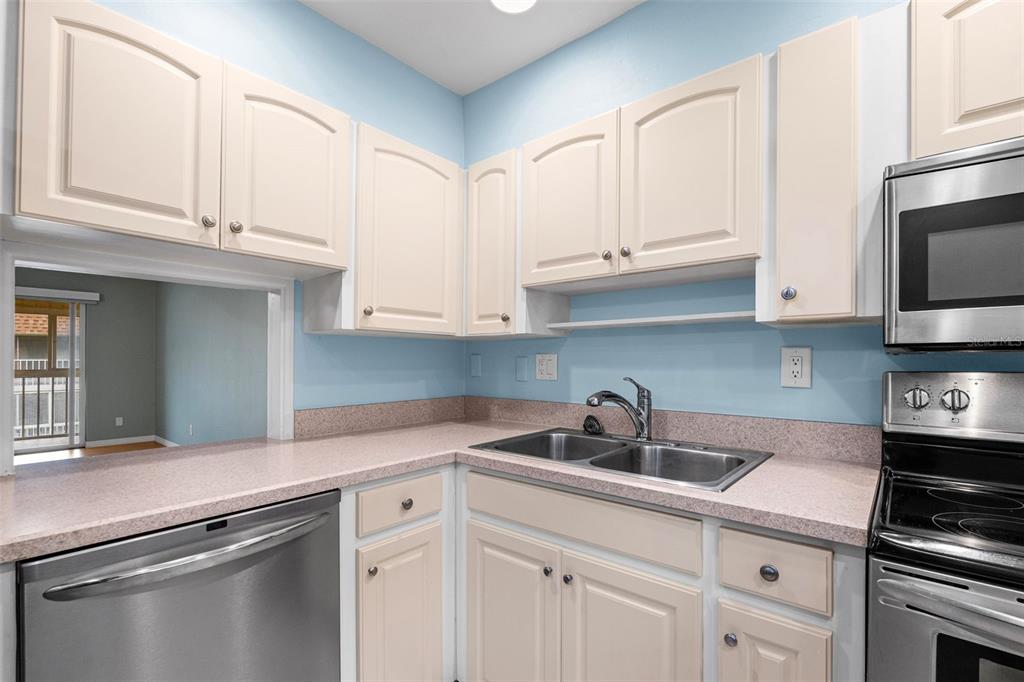 An empty room with light green walls, wood-look flooring, a ceiling fan, and sliding glass doors — 1310 GLEN OAKS DRIVE E UNIT 383E, SARASOTA, FL